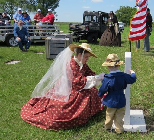 American Civil War lady and her son laying flowers at the grave site